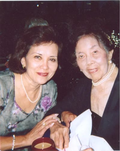Two women smiling together, one holding a cup