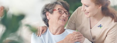 Staff member assisting a smiling resident in a common area