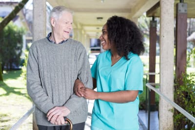 Caregiver assisting a senior in an outdoor setting