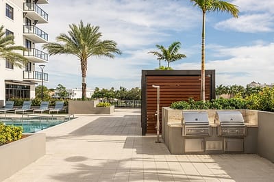 Outdoor grilling area near the pool with palm trees