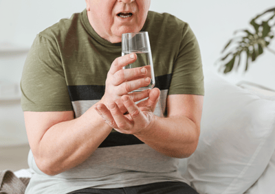 Resident holding a glass of water in a bright indoor setting
