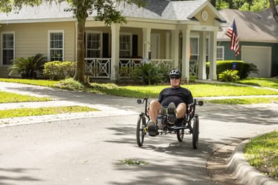 A resident riding a recumbent tricycle on a sunny street