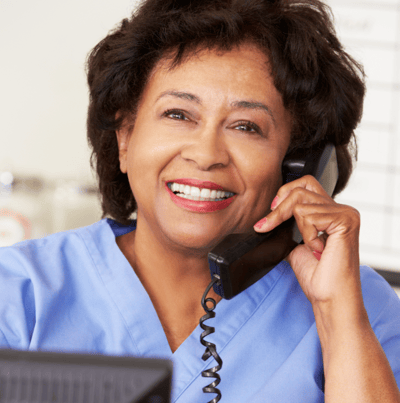 Smiling nurse talking on the phone in an office setting.
