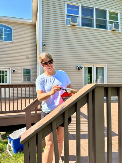 A staff member painting railings outdoors.