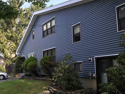 Exterior view of a blue house with greenery.