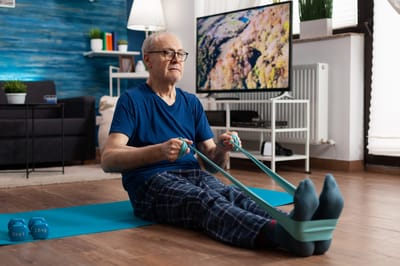 Senior man exercising indoors with resistance bands