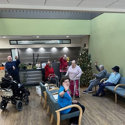 Residents waving in a common area decorated for the holidays