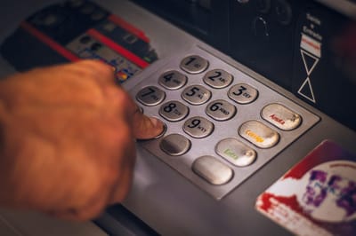 Photo of an ATM keypad with a hand