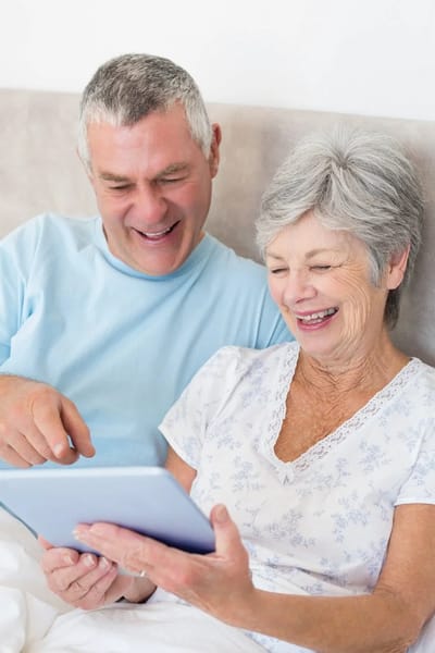 An older couple enjoying a tablet together in bed