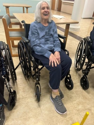 Resident smiling in a wheelchair in an indoor setting