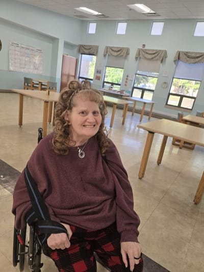 Resident smiling in a common area with tables