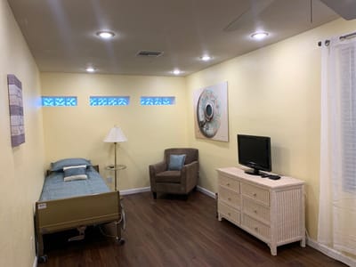 A cozy private resident room with a bed and chair