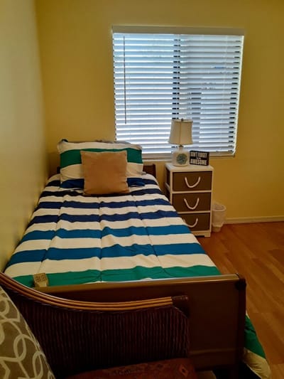 Cozy private room with a striped bedspread and natural light