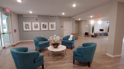 Bright common area with teal armchairs and art on the walls
