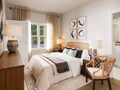 A well-decorated private resident room with a bed and chair