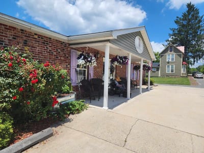 Covered porch with flowers and a resident in a wheelchair
