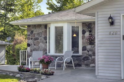 Entrance of a cottage with flowers and chairs outside