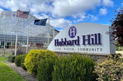 Hubbard Hill Village facility sign outside with flags