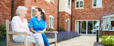 Senior resident enjoying conversation with staff outdoors