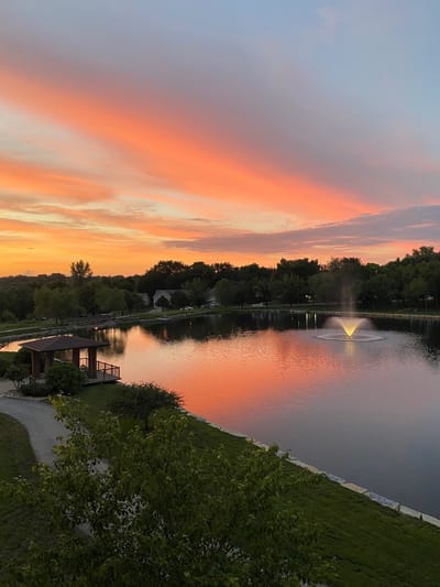 Sunset over a serene pond with fountain and gazebo