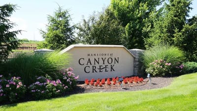 Exterior sign for Mansions at Canyon Creek with landscaping