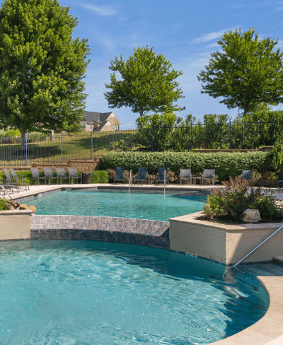 Outdoor swimming pool area surrounded by greenery