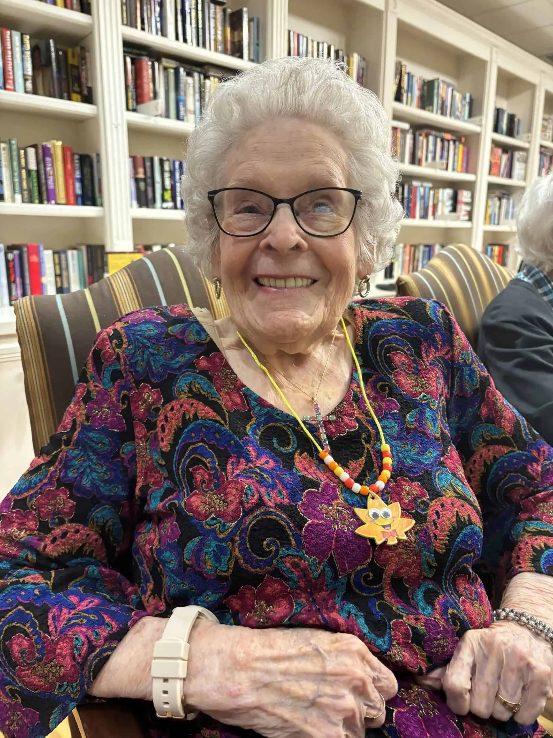 Smiling resident in a colorful top in a cozy setting