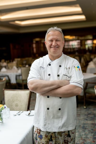 A chef smiling in a dining area of a senior living facility