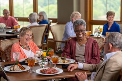 Residents enjoying a meal and conversation in the dining room