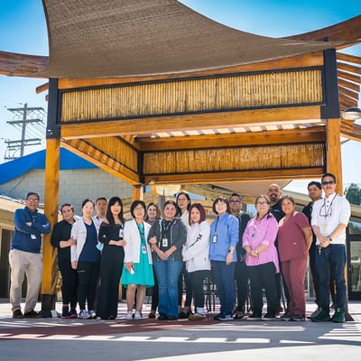 Facility staff posing together outdoors under a shaded area