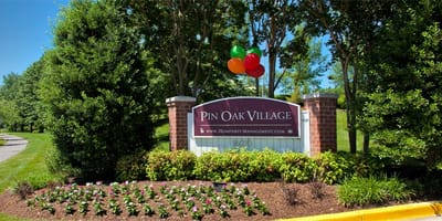 Entrance sign for Pin Oak Village surrounded by landscaping