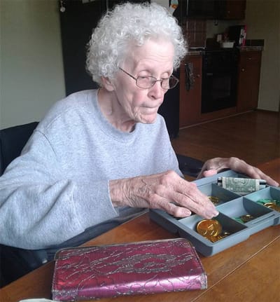 Elderly woman organizing coins at a table.
