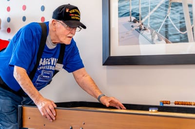 Senior playing shuffleboard indoors at the facility.