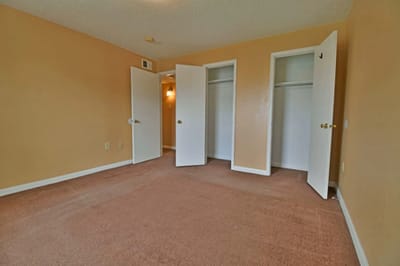 Empty resident room with beige walls and closets.