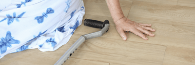 A hand reaching toward the floor with a cane