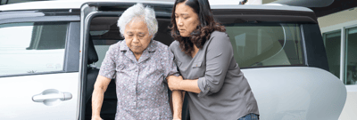 An older woman assisted from a vehicle