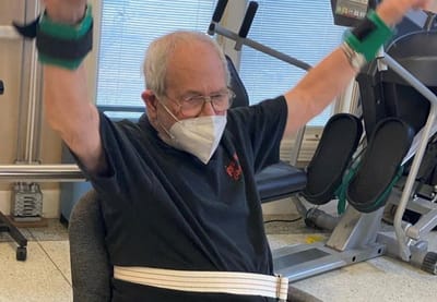 Senior man participating in an exercise activity indoors.
