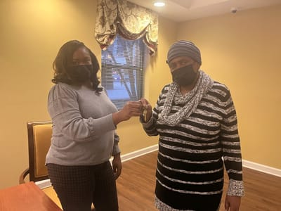 Two individuals exchanging keys indoors.