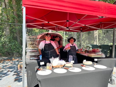 Smile from staff at a food service tent outdoors.