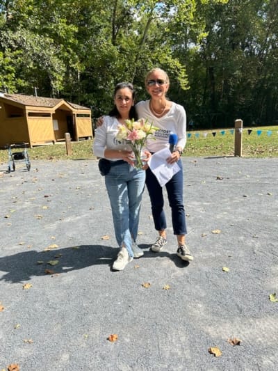 Two women posing outdoors with flowers.