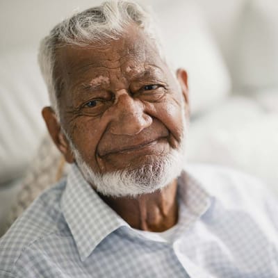 Close-up of an elderly man smiling warmly.