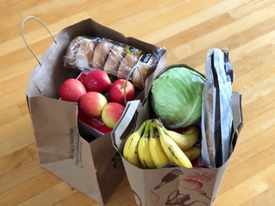 Grocery bags filled with fresh produce and bread.