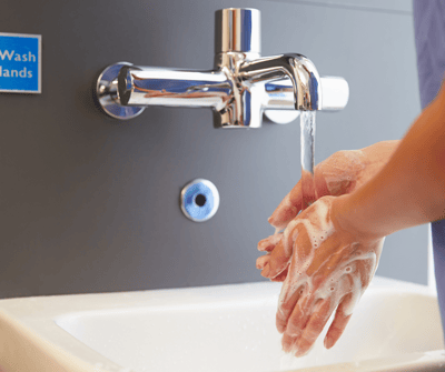 A person washing hands at a sink