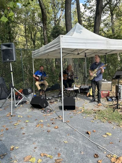 Musicians performing under a tent at an outdoor event.