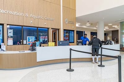 Reception area of a recreation center with staff and visitor.