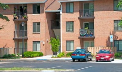 Exterior view of a senior living facility with cars.