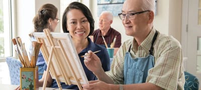 Smiling residents and staff engaging in an art activity.