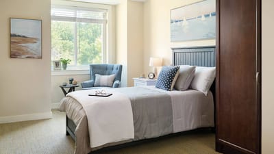 Cozy resident room with a bed and armchair.
