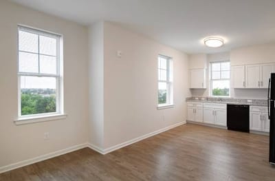 Empty kitchen area with modern appliances and wood flooring
