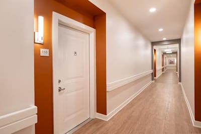 Bright hallway with a closed door and room number.